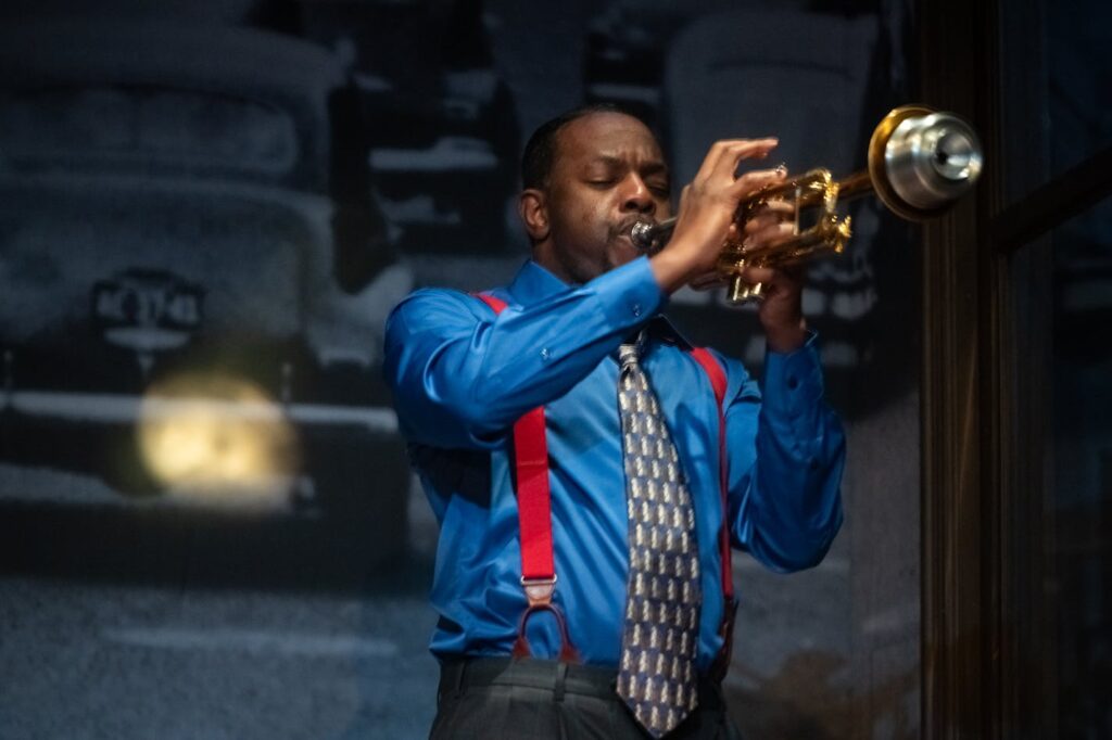 The cool cat blowing his muted trumpet in the corner of the Penumbra’s stage looks like he just stepped off the cover of a Miles Davis album. And Blue, as he is known, shares more than a striking resemblance with the jazz icon whose signature works include the groundbreaking 1959 album “Kind of Blue.”